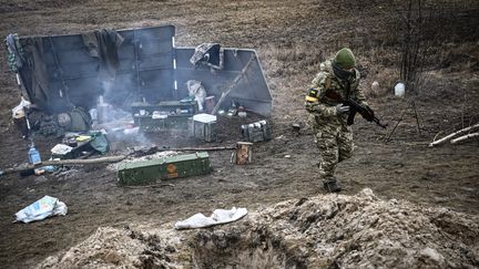 Un soldat ukrainien s'éloigne d'un feu de camp sur la ligne de front, au nord-est de Kiev, le 3 mars 2022. (ARIS MESSINIS / AFP)