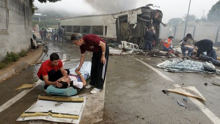 Deux hommes portent secours &agrave; une bless&eacute;e apr&egrave;s le d&eacute;raillement du train au niveau de Saint-Jacques-de-Compostelle (Espagne), le 24 juillet 2013. (XOAN A. SOLER / LA VOZ DE GALICIA / AFP)