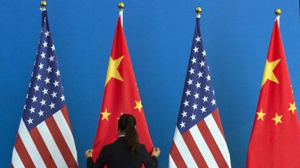 Femme ajustant les drapeaux américains et chinois en vue d'une négociation entre les deux pays.
 (AFP PHOTO / POOL  NG HAN GUAN / POOL / AFP)