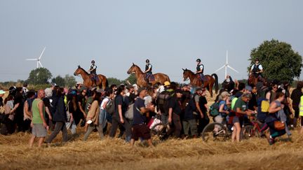 Des gendarmes à cheval empêchent les manifestants d'aller dans les champs, à Saint-Martin-lès-Melle (Deux-Sèvres), alors qu'ils se dirigent vers Saint-Sauvant (Charente-Maritime) pour protester contre le projet de mégabassines. (ROMAIN PERROCHEAU / AFP)