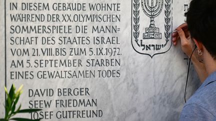 Un homme repeint la plaque du mémorial des victimes de l'attentat perpétré lors des Jeux olympiques de Munich en 1972.&nbsp; (INA FASSBENDER / AFP)