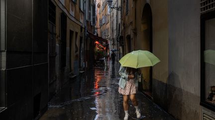 Des passants tentent d'éviter les flaques d'eau formées par la pluie le 26 octobre 2024, à Nice. (XAVIER DUVOT / HANS LUCAS / AFP)