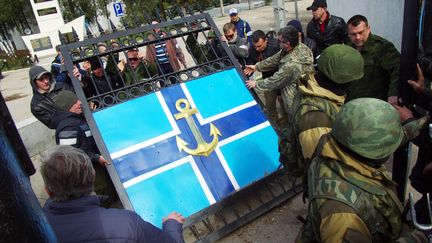 Des miliciens pro-russes d&eacute;montent le portail&nbsp;du si&egrave;ge de la marine &agrave; S&eacute;bastopol, en Crim&eacute;e, avant de prendre possession des lieux, mercredi 19 mars 2014. (VASILIY BATANOV / AFP)