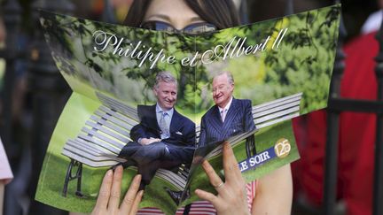 Une touriste lit le suppl&eacute;ment du journal Le Soir consacr&eacute; &agrave; la passation de pouvoir entre le roi des Belges Albert II et son fils Philippe &agrave; Bruxelles (Belgique), le 21 juillet 2013. ( PHILIPPE WOJAZER / REUTERS)