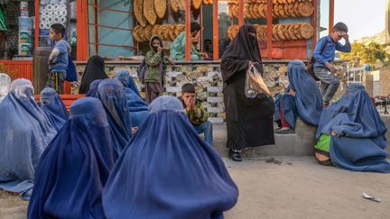 Des femmes vêtues en burqa attendent devant une boulangerie pour recevoir des dons de pain à Kaboul, en Afghanistan, le 20 octobre 2021. (BULENT KILIC / AFP)