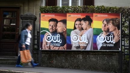 Une femme passe devant une affiche électorale pour le référendum sur le mariage pour tous, le 22 septembre 2021, à Lausanne (Suisse). (FABRICE COFFRINI / AFP)