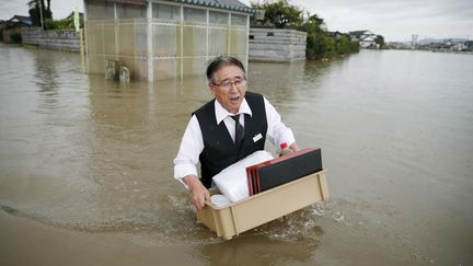 Un homme transporte des affaires&nbsp;à l'abri des inondations&nbsp;à Oyama. Le typhon Etau a provoqué la crue de la rivière Omoigawa qui a chassé 100 000 personnes de leurs maisons,&nbsp;le 10 septembre 2015. (KYODO KYODO / REUTERS)