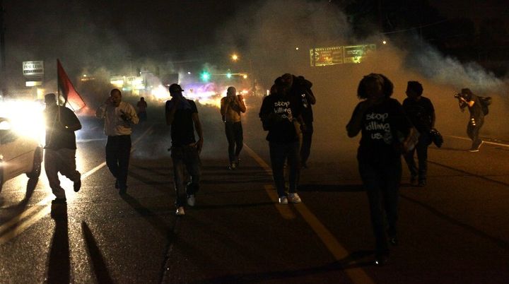 Des manifestants se dispersent apr&egrave;s des tirs de gaz lacrymog&egrave;ne effectu&eacute;s par la police anti-&eacute;meute &agrave; Ferguson (Etats-Unis), le 17 ao&ucirc;t 2014. (JOSHUA LOTT / GETTY IMAGES NORTH AMERICA / AFP)