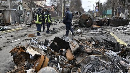 Des ingénieurs des urgences ukrainiennes examinent des véhicules détruits dans les rues de Boutcha, le 5 avril 2022. (GENYA SAVILOV / AFP)