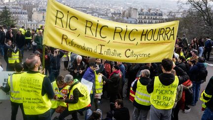 Des "gilets jaunes" brandissent une pancarte pour le RIC à Montmartre à Paris, le 23 mars 2019. (LAURE BOYER / HANS LUCAS)