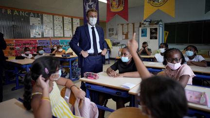 Emmanuel Macron pose avec des élèves masqués dans une école primaire à Marseille, le 2 septembre 2021. (DANIEL COLE / POOL / AFP)