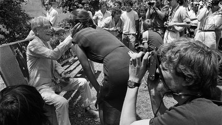 Rencontres internationales de la photographie d'Arles, juillet 1981 : le célèbre photographe français Jacques-Henri Lartigue s'adresse à l'écrivain et la photographe américaine Linda Wolf,&nbsp;devant un parterre de photographes. (GERARD FOUET / AFP)