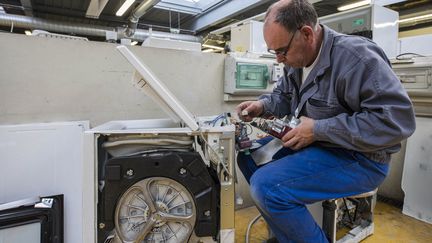 Un technicien réparant une machine à laver (Photo d'illustration). (JEAN-MICHEL DELAGE / HANS LUCAS VIA AFP)