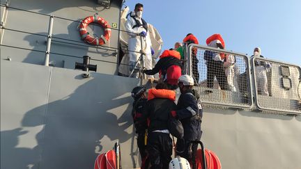 Des migrants secourus en Méditerranée montent à bord d'un navire de la marine maltaise, le 23 août 2019. (ANNE CHAON / AFP)