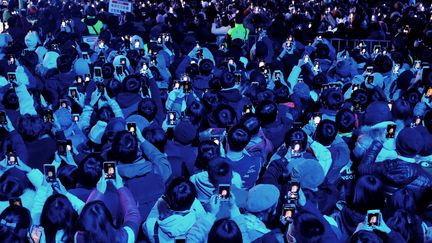 A Taiwan, les habitants de Taipei ont été nombreux à immortaliser sur leur téléphone le feu d'artifice tiré depuis le gratte-ciel Taipei 101. (SAM YEH / AFP)