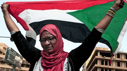 Une femme brandit le drapeau soudanais durant le soulèvement populaire contre le président Omar el-Béchir, le 12 septembre 2019 à Khartoum. (EBRAHIM HAMID / AFP)