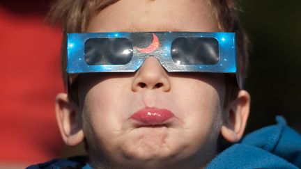 Un jeune gar&ccedil;on observe l'&eacute;clipse solaire &agrave; Berlin (Allemagne), le 20 mars 2015. (STEFFI LOOS / AFP)