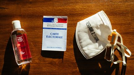 Le "kit de l'électeur" des municipales 2020 : une bouteille de gel&nbsp;hydroalcoolique, une carte électorale et un masque&nbsp;dans un bureau de vote à Paris.&nbsp; (MATHIEU MENARD / HANS LUCAS)