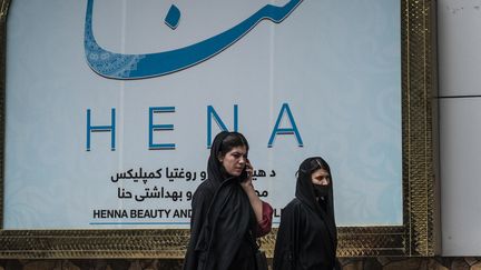 Des femmes passent devant un salon de beauté dans le quartier de Shahr-e Naw à Kaboul (Afghanistan), le 4 juillet 2023. (WAKIL KOHSAR / AFP)