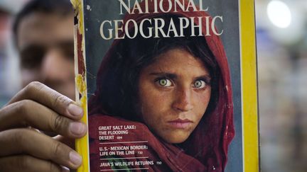 En 2016, un libraire pakistanais brandit un exemplaire du "National Geographic"&nbsp;avec "l'Afghane aux yeux verts" en couverture. (B.K. BANGASH/AP/SIPA / AP)