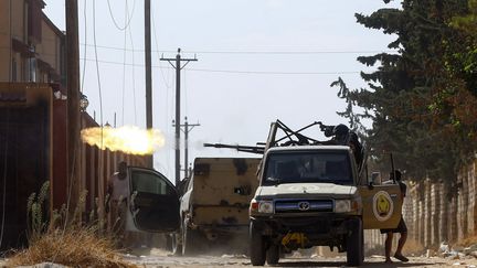 Un combattant loyal au Gouvernement libyen d'union nationale (GNA), reconnu internationalement, tire avec une arme montée sur un camion lors d'affrontements avec les forces fidèles à l'homme fort Khalifa Haftar à Ain Zara, dans la banlieue de Tripoli, le 7 septembre 2019.&nbsp; (MAHMUD TURKIA / AFP)