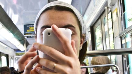 Une femme tape sur son smartphone&nbsp;dans le m&eacute;tro &agrave; Paris en 2010. (HERVE DE GUELTZL / PHOTONONSTOP / AFP)