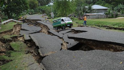 Une camionnette transportant une vistime du tremblement de terre roule sur une route d&eacute;truite &agrave; Tuway (Philippines), le 7 f&eacute;vrier 2012. (TED ALJIBE / AFP)