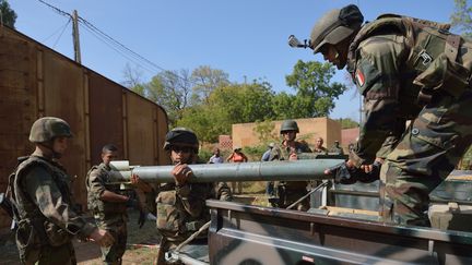 Des soldats fran&ccedil;ais d&eacute;chargent une roquette trouv&eacute;e dans un stock de munitions des islamistes, pr&egrave;s de Diabali (Mali), le 23 janvier 2013. (ERIC FEFERBERG / AFP)