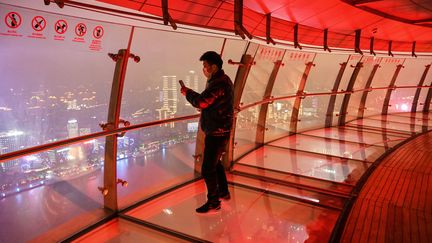 Un homme prend des photos depuis le sommet de la tour Perle de l'Orient, à Shanghai (Chine), le 12 mars 2020. (HECTOR RETAMAL / AFP)