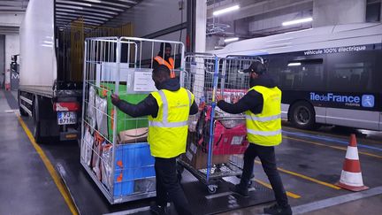 Deux chauffeurs de l'entreprise Amazon déchargent leurs colis dans la zone balisée du dépôt de bus de la RATP de la porte d'Orléans, dans le 14e arrondissement de Paris.&nbsp; (SOPHIE AUVIGNE / RADIO FRANCE)