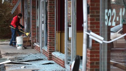 Un homme nettoie les d&eacute;bris de baies vitr&eacute;es fracass&eacute;es, &agrave; Dellwood.&nbsp;Barack Obama et les parents de Michael Brown avaient appel&eacute; au calme, lundi, avant l'annonce de la d&eacute;cision du grand jury. (JUSTIN SULLIVAN / GETTY IMAGES NORTH AMERICA)