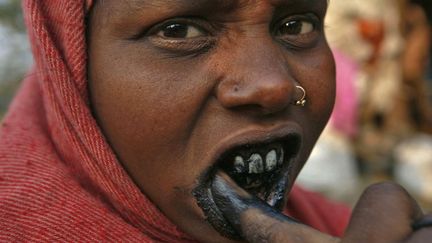 Une femme se brosse les dents avec du charbon dans un bidonville pr&egrave;s de New Delhi (Inde), le 10 novembre 2011. (PARIVARTAN SHARMA / REUTERS)