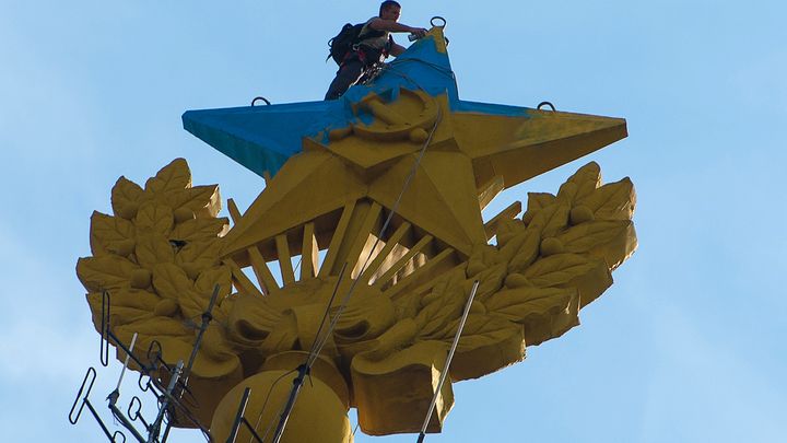 Un travailleur repeint l'&eacute;toile de l'immeuble&nbsp;Kotelnicheska&iuml;a, &agrave; Moscou (Russie), en partie recouvert de bleu par des militants. (RAMIL SITDIKOV / RIA NOVOSTI / AFP)