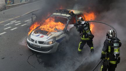 Les pompiers éteignent l'incendie d'une voiture de police, le 18 mai 2016, à Paris. (MICHAUD GAEL / NURPHOTO / AFP)