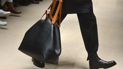 Chez Jil Sander, le nouveau directeur créatif Rodolfo Paglialunga était très attendu pour sa première collection dans la maison allemande. Atmosphère sobre et rétro parfois égayée par des chausses orange vif ou un col roulé jaune. "J'ai essayé de rendre la collection facilement approchable par les clients. Je ne voulais pas créer l'image d'un homme abstrait, idéalisé. Je voulais injecter un sens de la vie réelle", avait fait savoir le couturier qui n'habillait jusqu'ici que les femmes. 
 (TIZIANA FABI / AFP)