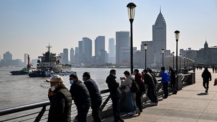 Des personnes se tiennent sur la promenade du Bund, le long de la rivière Huangpu à Shanghai, le 21 décembre 2022. (HECTOR RETAMAL / AFP)