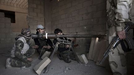 Des rebelles syriens en faction dans un immeuble &agrave; Deir Ezzor, dans l'est de la Syrie, le 27 f&eacute;vrier 2013.&nbsp; (ZAC BAILLIE / AFP)