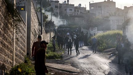 Des personnes se rassemblent le long d'une route lors d'un raid de l'armée israélienne dans le camp de réfugiés palestiniens de Jénine, en Cisjordanie occupée, le 7 mars 2023. (JAAFAR ASHTIYEH / AFP)