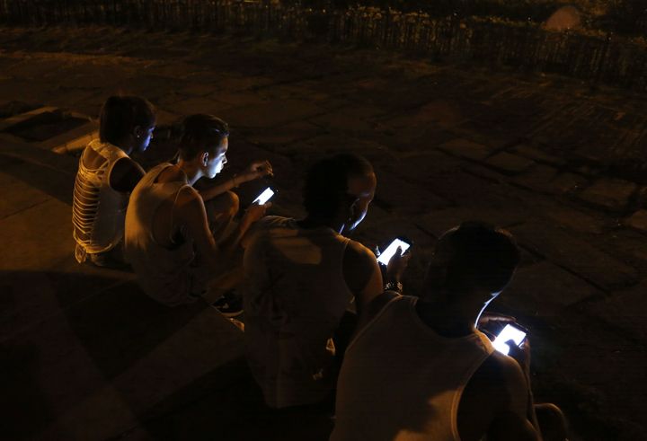 De jeunes Cubains consultent leurs smartphones, dans une rue de La Havane (Cuba), le 1er juillet 2015.&nbsp; (DESMOND BOYLAN / AP / SIPA / AP)