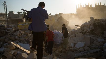 Des Syriens marchent sur les ruines de leur maison &agrave; Azaz, dans le nord du pays, le 19 ao&ucirc;t 2012. (PHIL MOORE / AFP)