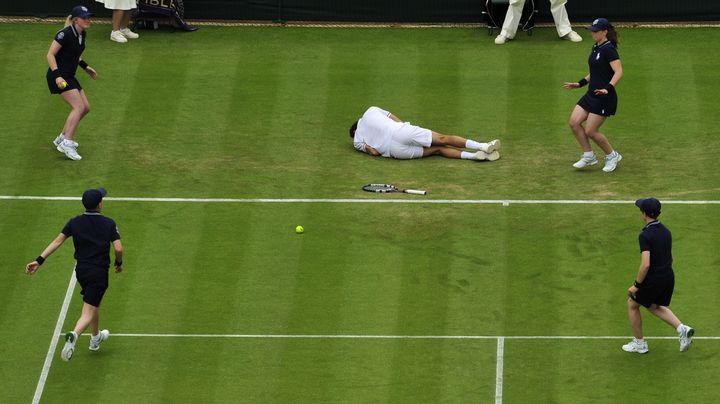 Les ramasseurs de balles se pr&eacute;cipitent vers Julien Benneteau, &agrave; terre apr&egrave;s une glissade, le 26 juin 2013 &agrave; Wimbledon (Grande-Bretagne). (GLYN KIRK / AFP)