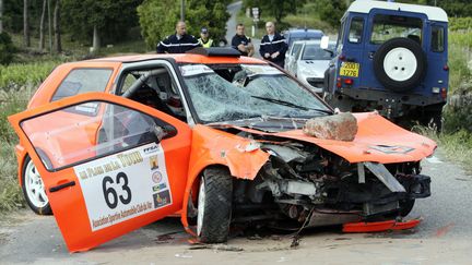 Pompiers et gendarmes s'affairent autour de la voiture de rallye accident&eacute;e dont la sortie de route a fait deux morts et quinze bless&eacute;s &agrave; Plan-de-la-Tour (Var), le 19 mai 2012. (JEAN-CHRISTOPHE MAGNENET / AFP)