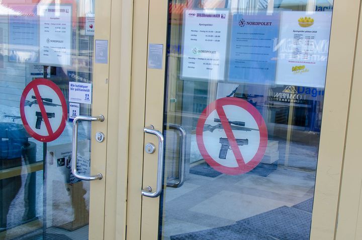 Des panneaux interdisant le port d'armes à feu, le 27 mars 2018, à l'entrée du supermarché de Longyearbyen. (YANN THOMPSON / FRANCEINFO)