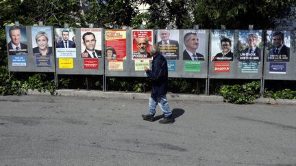 Un homme passe devant les panneaux électoraux dans la commune de Saint-André-de-la-Roche (Alpes-Maritimes), lundi 10 avril 2017. (ERIC GAILLARD / REUTERS)