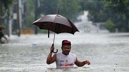 Un Philippin marche dans une rue inond&eacute;e de Manille (Philippines), le 23 septembre 2013. (TED ALJIBE / AFP)