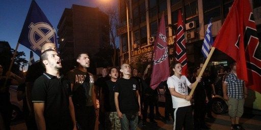 Défilé de l'Aube dorée en juin 2012 à Thessalonique avec le drapeau du parti (sorte de croix noire sur fond rouge) et le drapeau "occident" en blanc sur fond noir. (AFP PHOTO / SAKIS MITROLIDIS)