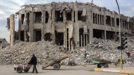 Un Irakien pousse une charrette devant les décombres d'un bâtiment à Mossoul, le 13 janvier 2019. (ZAID AL-OBEIDI / AFP)