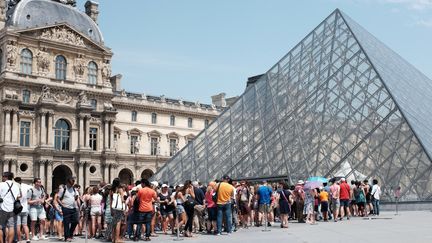 Des visiteurs attendent à l'entrée de la pyramide du Louvre. Juillet 2015.
 (MIGUEL MEDINA / AFP)