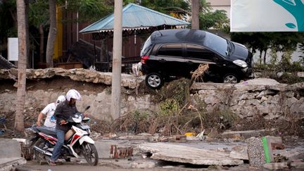 Un homme tente de conduire sa moto à Palu, sur l'île des Célèbes en Indonésie, le 29 septembre 2018. La veille, un séisme et un tsunami ont frappé l'île. (BAY ISMOYO / AFP)