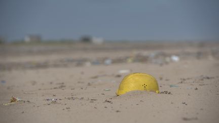 Un casque de chantier et des déchets en plastique sur la plage de Lagos (Nigéria), le 2 juin 2018. (STEFAN HEUNIS / AFP)